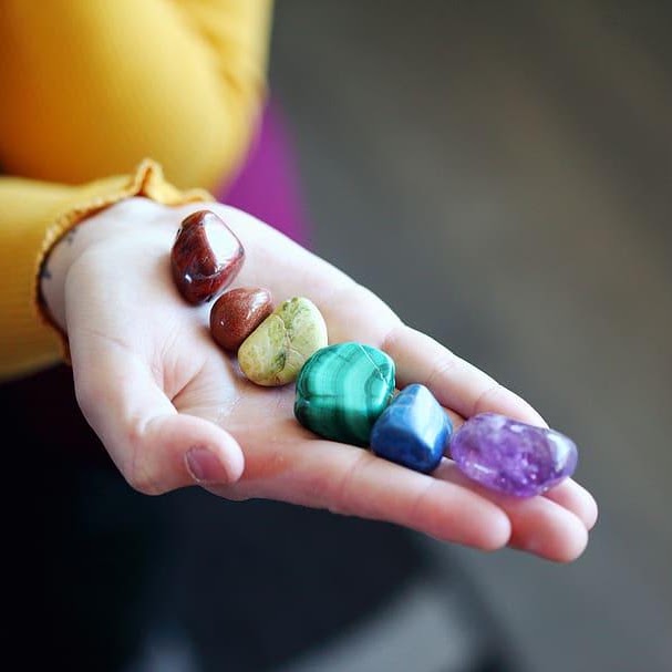 An open hand holding a small collection of colorful crystals