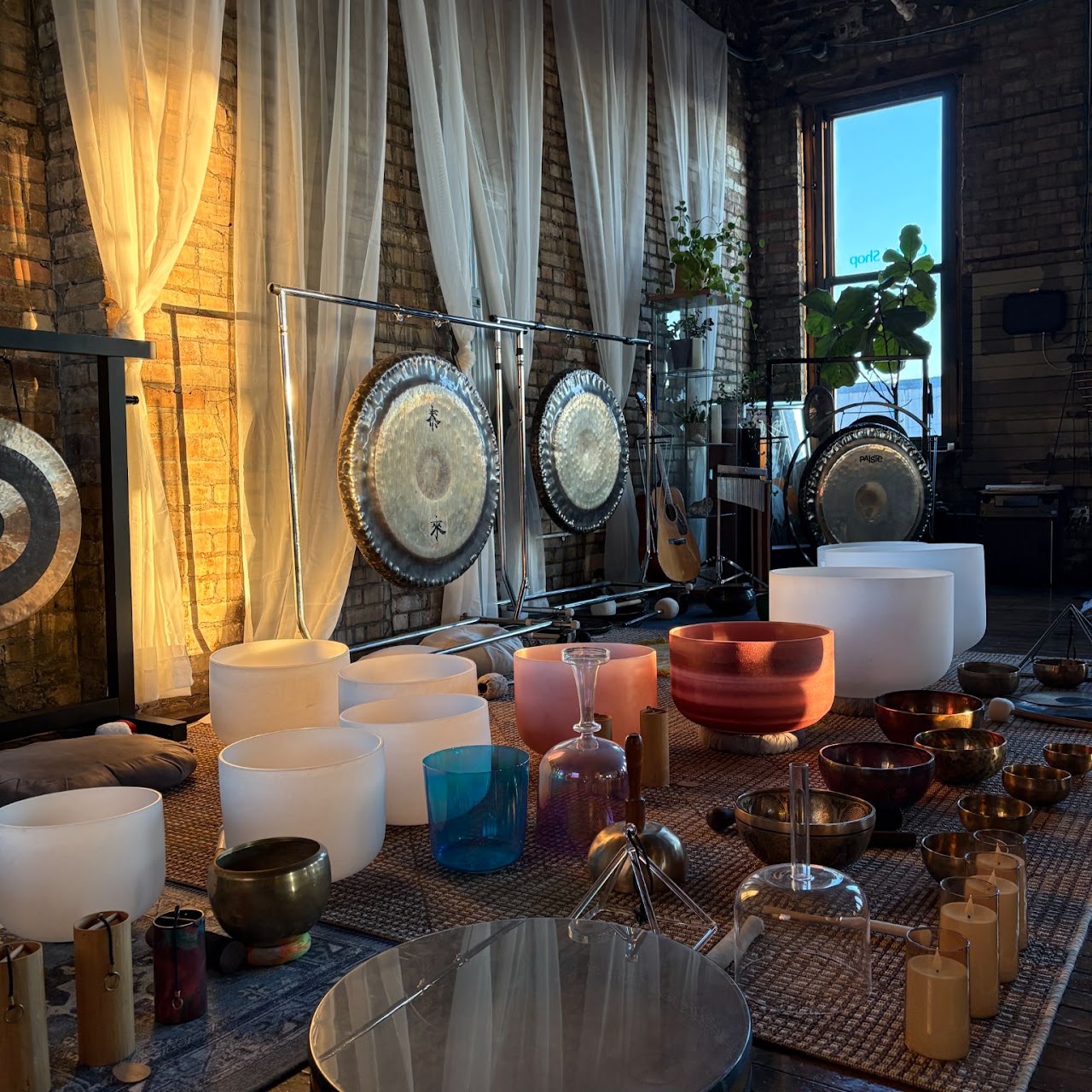 Candlelit room with a collection of gongs and singing bowls